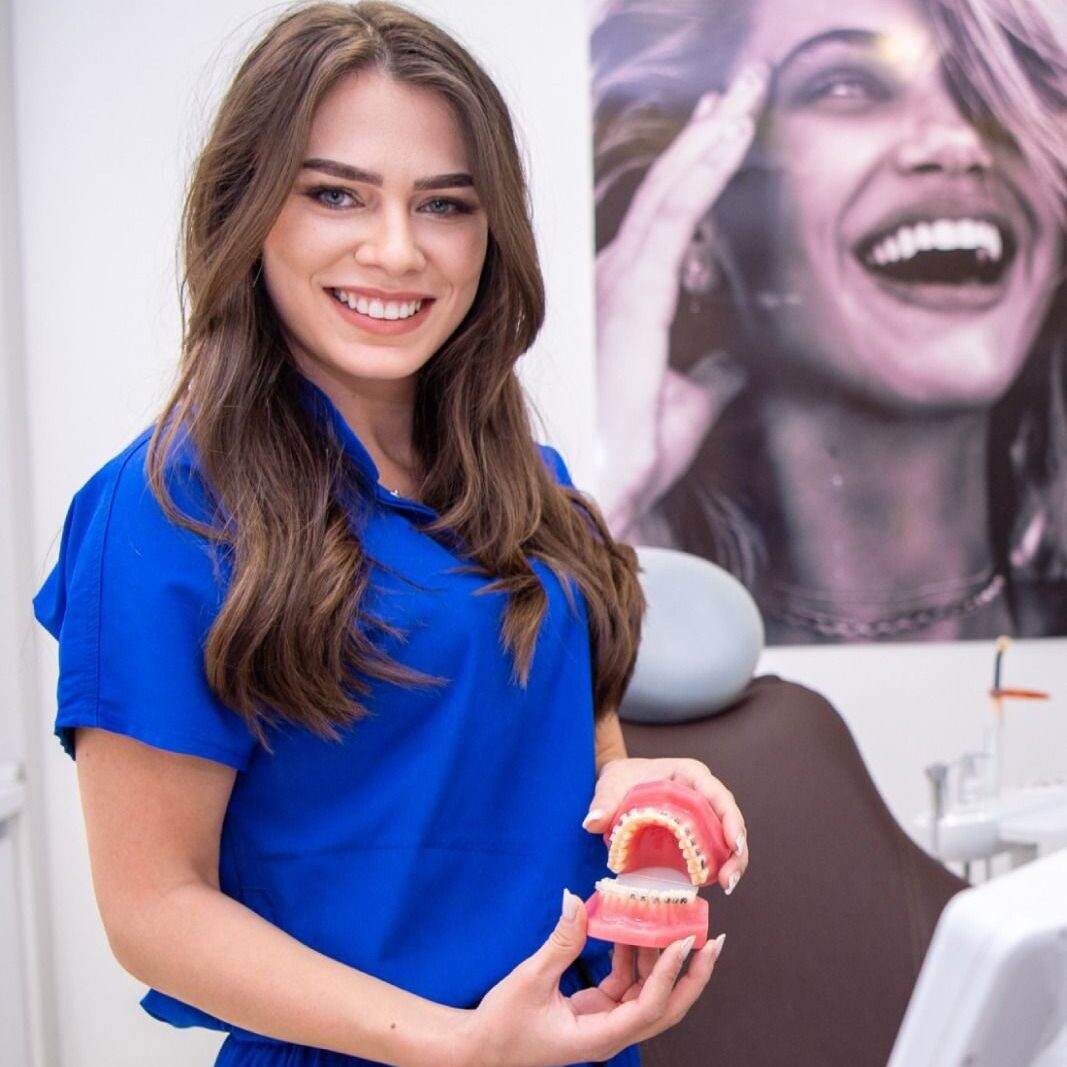 Femeie zâmbitoare cu un model de dinte la Clinica de Zâmbete, clinică stomatologică din Florești